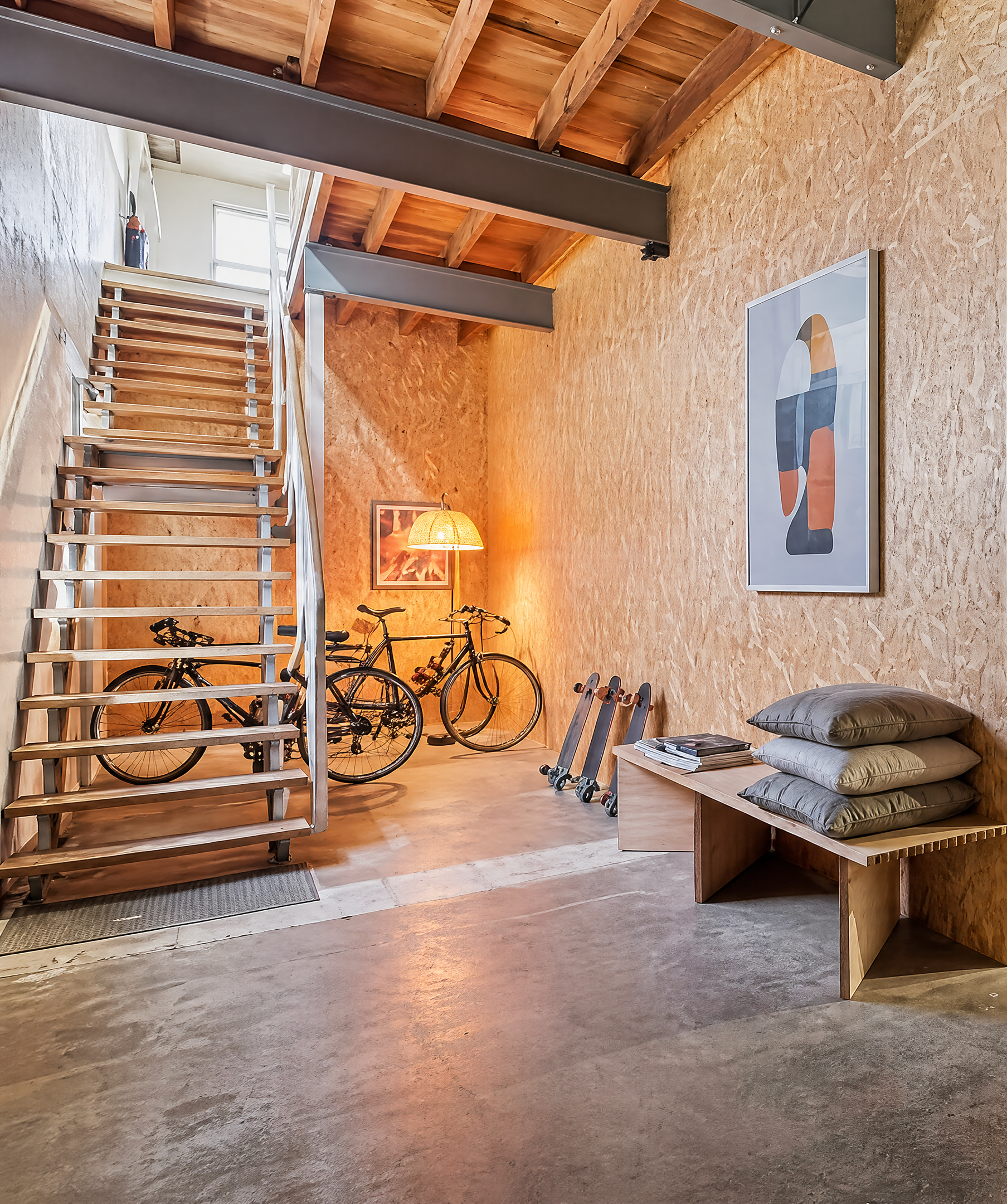The entry vestibule at Sturt Street — OSB-clad walls, polished concrete floor, timber stairs leading to the upper floor.