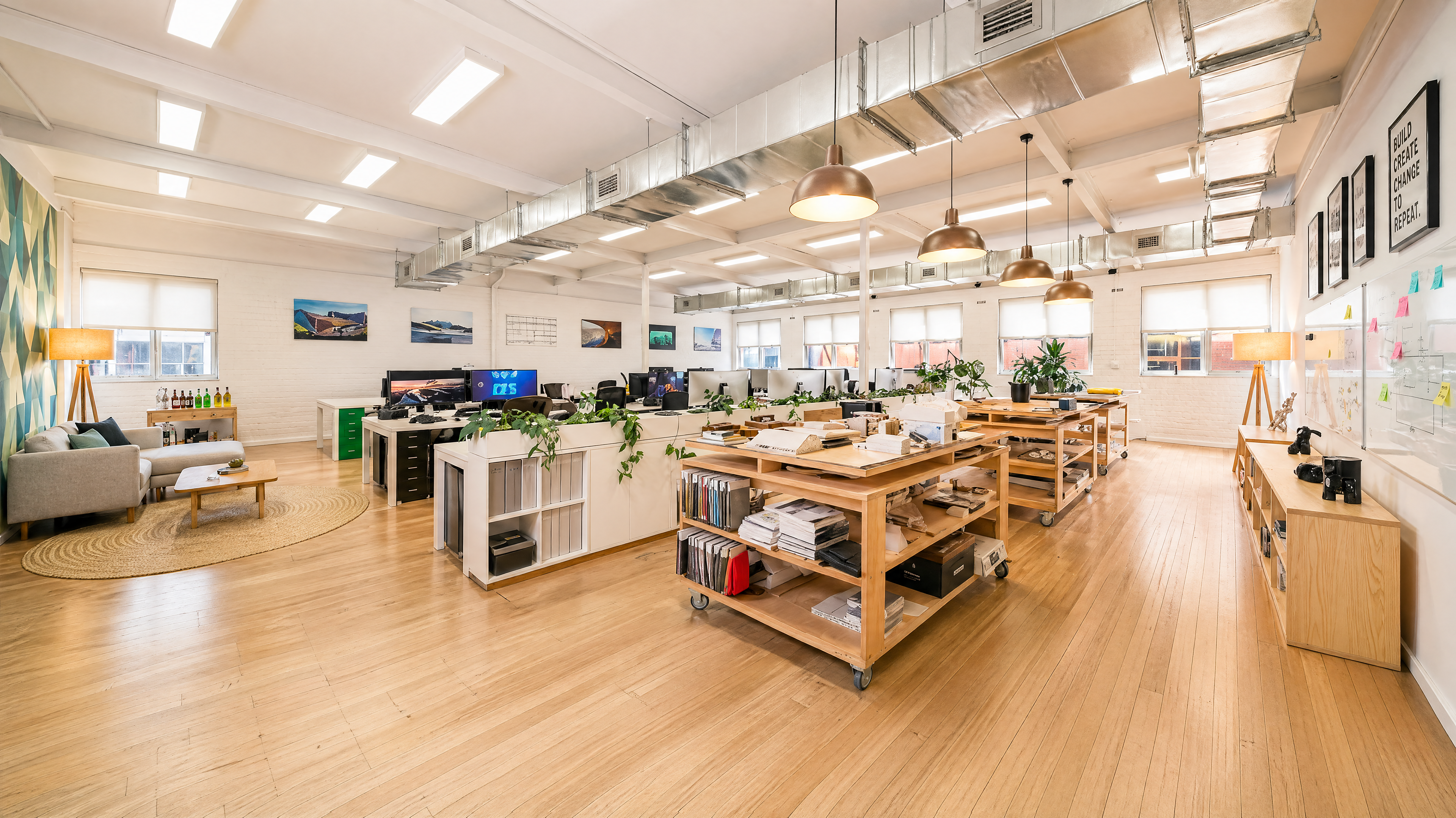 Upper floor wide shot — work tables, pendant lighting, exposed ducting.